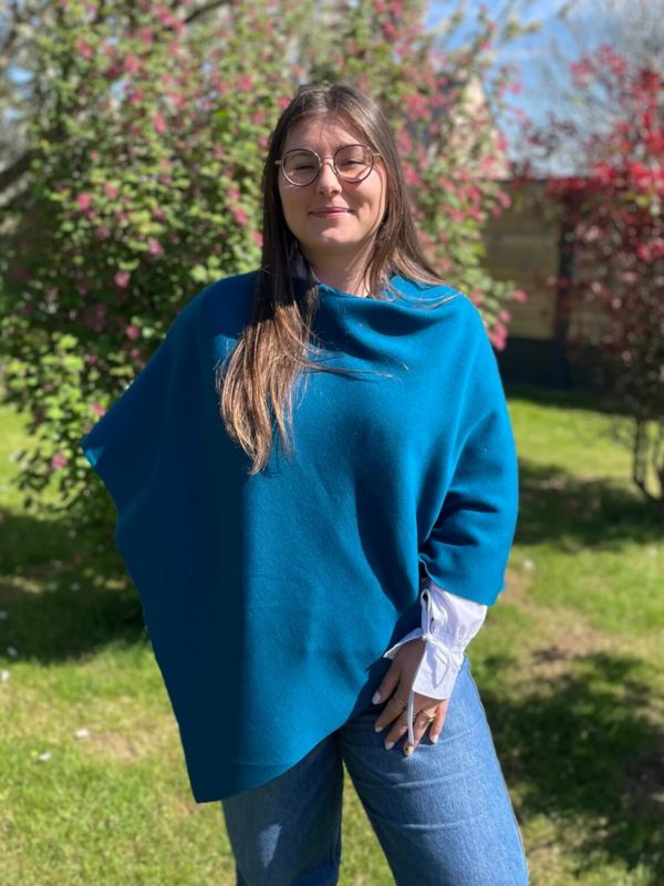 Poncho en 100% mérinos extrafin couleur bleu canard porté par une femme dans un jardin ensoleillé