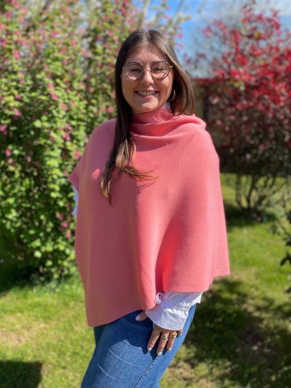Poncho en 100% mérinos extrafin couleur bois de rose porté par une femme dans un jardin ensoleillé