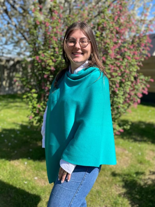 Poncho en 100% mérinos extrafin couleur calanque porté par une femme dans un jardin ensoleillé