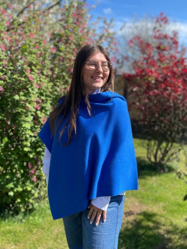 Poncho en 100% mérinos extrafin couleur cobalto porté par une femme dans un jardin ensoleillé
