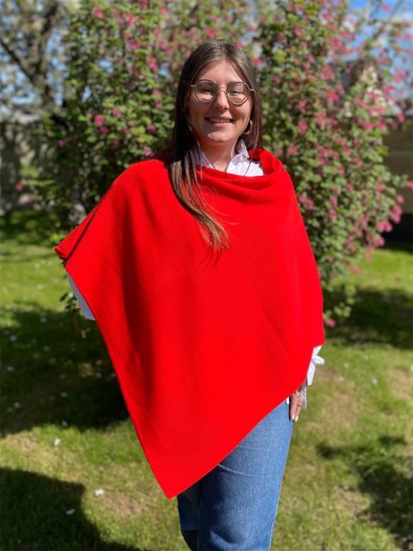 Poncho en 100% mérinos extrafin couleur coquelicot porté par une femme dans un jardin ensoleillé
