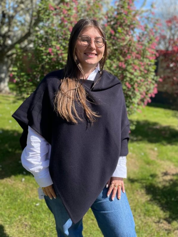 Poncho en 100% mérinos extrafin couleur marine porté par une femme dans un jardin ensoleillé