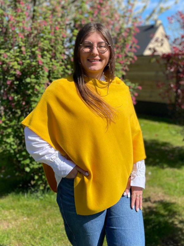 Poncho en 100% mérinos extrafin couleur safran porté par une femme dans un jardin ensoleillé