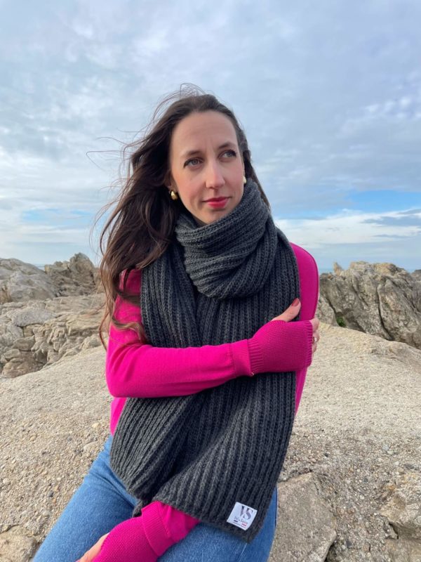 Echarpe Anglaise de couleur anthracite portée par une femme assise sur un rocher